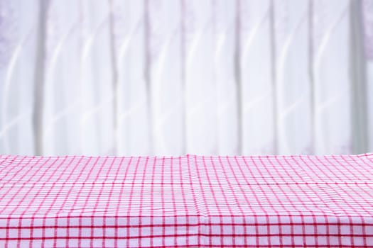 Empty table with red checkered tablecloth with bright background.  For food and product display montage.
