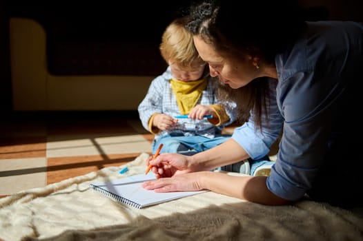 A mother and child bond during a creative drawing session at home, enjoying quality time together in a warmly lit atmosphere.