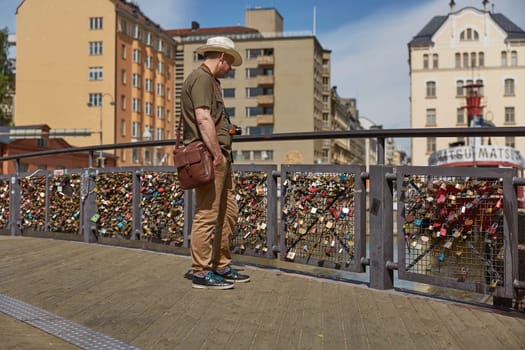 HELSINKI, FINLAND - JULY 10, 2017: Tourist man observing lovelocks attached to a bridge of love railing in central Helsinki, Finland.
