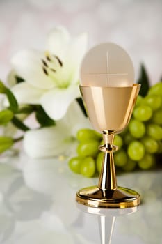 Holy communion a golden chalice with grapes and bread wafers