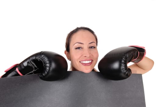 A young gorgeous woman with black boxing gloves holding a black.board looking over and smiling, isolated for white background.