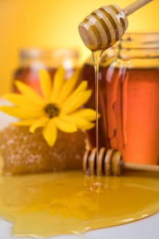 Honey dripping from a wooden honey dipper in a jar