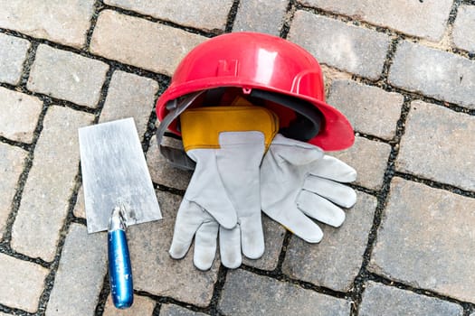 red helmet, trowel and work gloves on stone ground