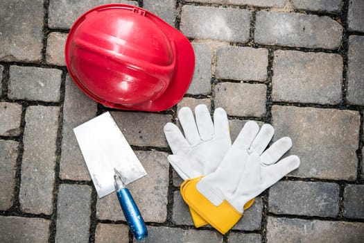 red helmet, trowel and work gloves on stones