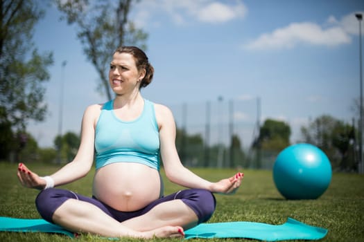 Healthy pregnant woman doing yoga in nature