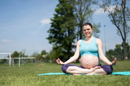 Healthy pregnant woman doing yoga in nature