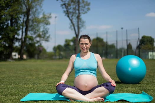 Healthy pregnant woman doing yoga in nature