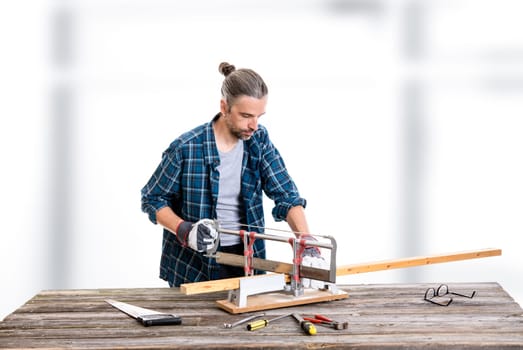 worker in blue plaid  shirt sawing wood