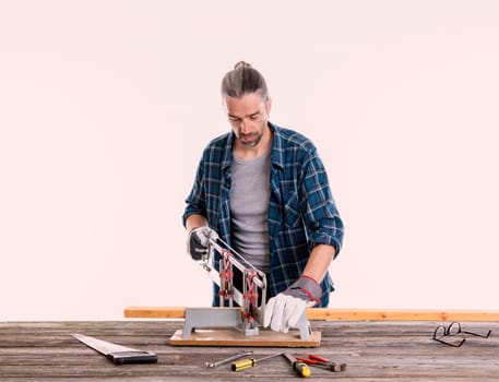 worker in blue plaid  shirt sawing wood