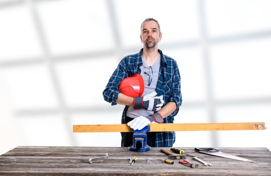 worker in blue plaid  shirt with red helmet on workbench