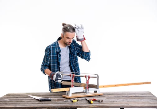 worker in blue plaid  shirt sawing wood