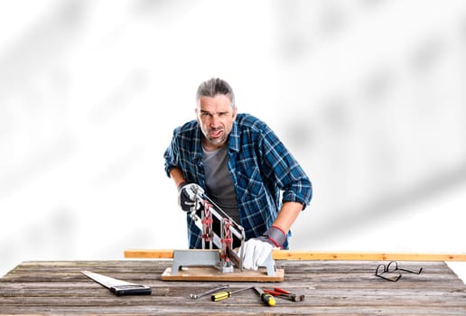 worker in blue plaid  shirt sawing wood