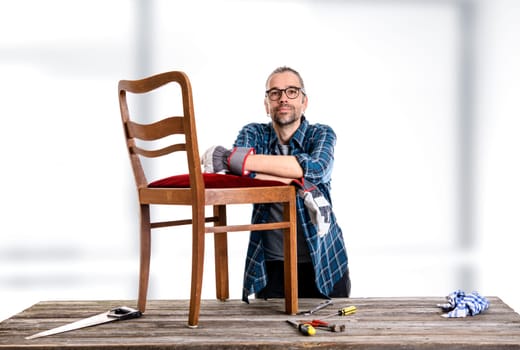 worker in blue plaid  shirt repair old chair