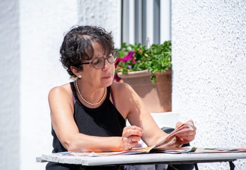 portrait of mature brunette  woman reading magazine in the garden