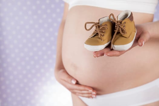 Pregnant woman holding baby shoes in her hands