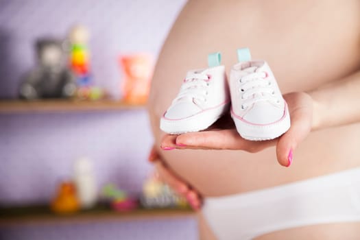 Pregnant woman holding baby shoes in her hands