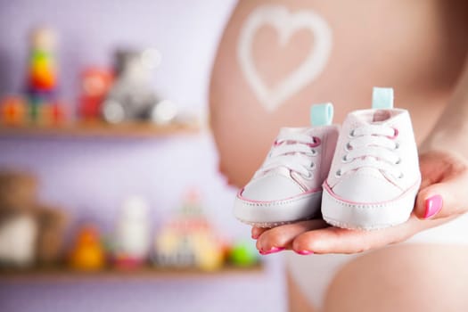 Pregnant woman holding baby shoes in her hands