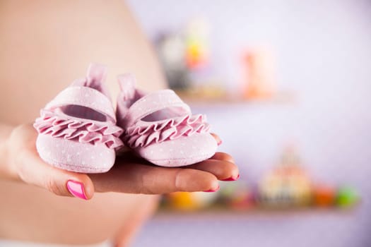 Pregnant woman holding baby shoes in her hands