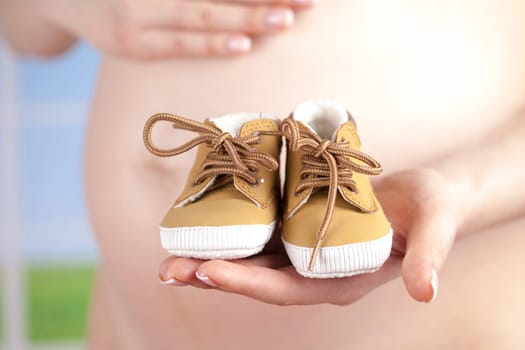 Pregnant woman holding baby shoes in her hands