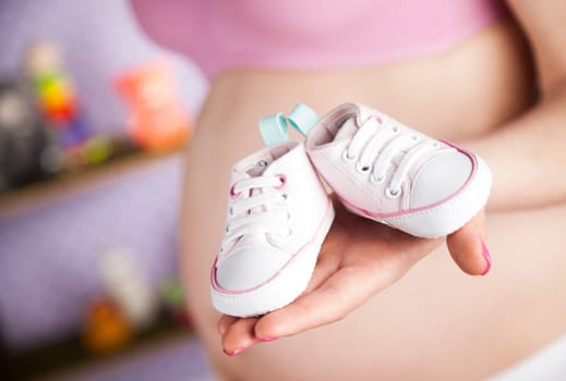 Pregnant woman holding baby shoes in her hands