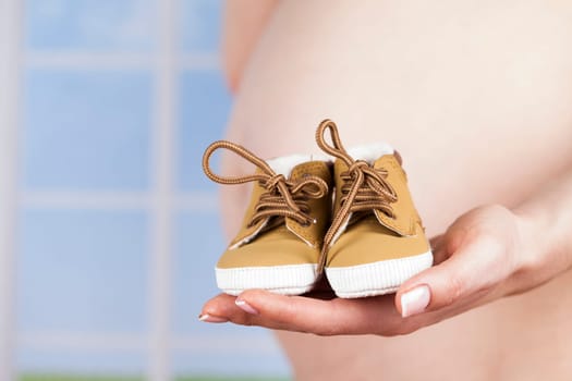 Pregnant woman holding baby shoes in her hands