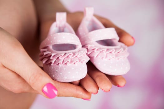 Pregnant woman holding baby shoes in her hands