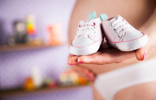 Pregnant woman holding baby shoes in her hands