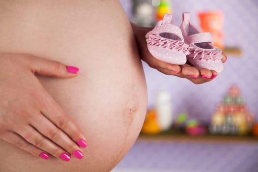 Pregnant woman holding baby shoes in her hands