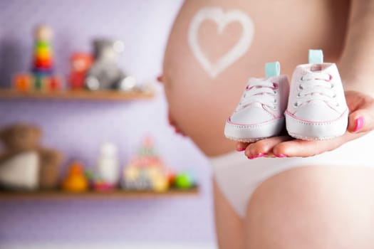 Pregnant woman holding baby shoes in her hands