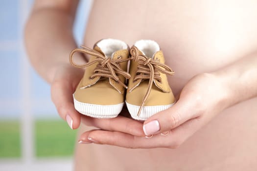 Pregnant woman holding baby shoes in her hands