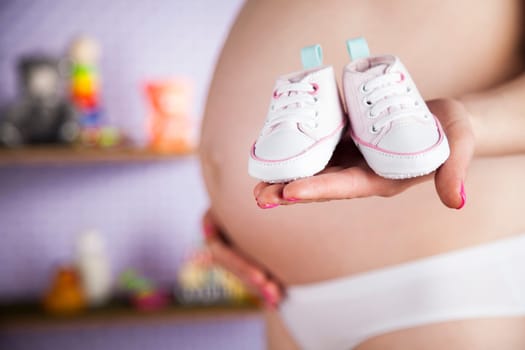 Pregnant woman holding baby shoes in her hands