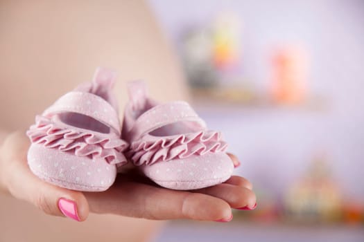 Pregnant woman holding baby shoes in her hands