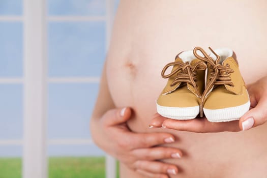 Pregnant woman holding baby shoes in her hands