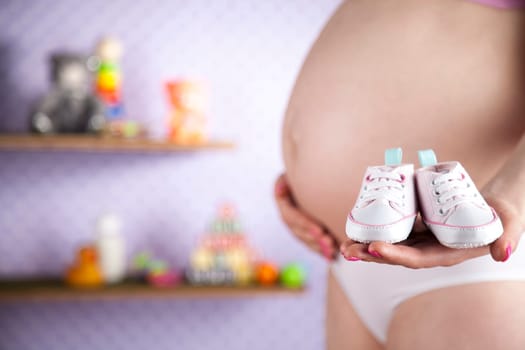 Pregnant woman holding baby shoes in her hands
