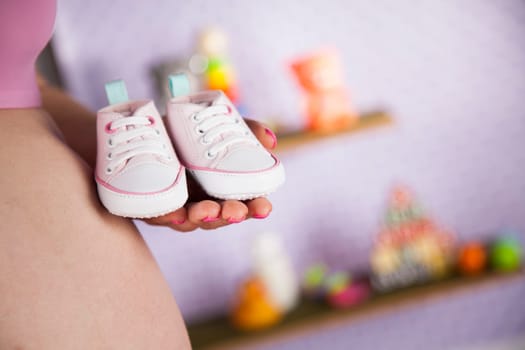 Pregnant woman holding baby shoes in her hands