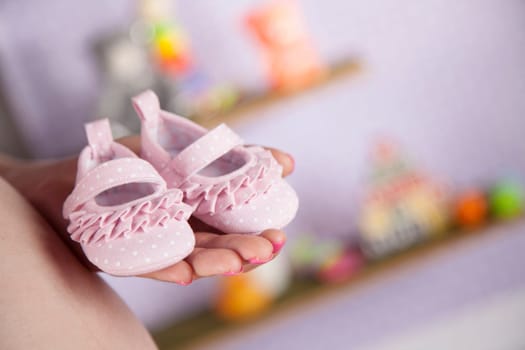 Pregnant woman holding baby shoes in her hands