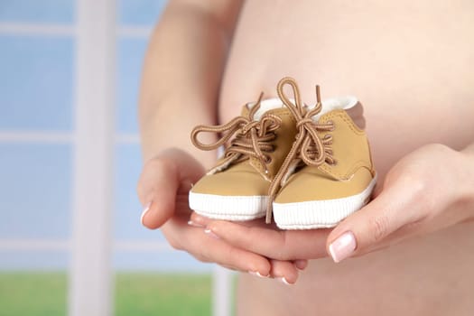Pregnant woman holding baby shoes in her hands