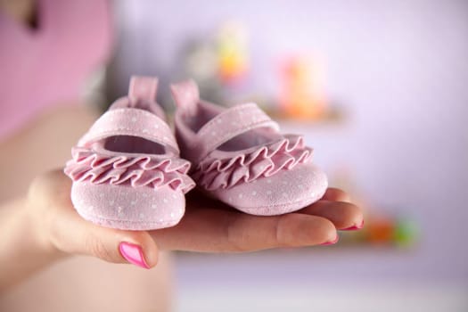 Pregnant woman holding baby shoes in her hands