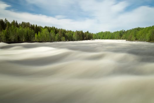 The rapids at Renforsen in Vindeln, Sweden with a partly cloudy sky.