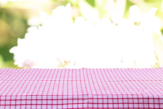 Empty table with red checkered tablecloth and bright natural background. For your food and product display montage.
