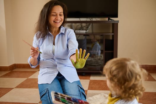 Happy mother bonding with her child through painting activity, creating art and enjoying quality time during maternity leave, capturing the essence of togetherness and creativity.
