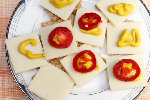 Snack of crackers with red jalapenos, cheese and mustard. Appetizer of cheese mustard pepper slices.