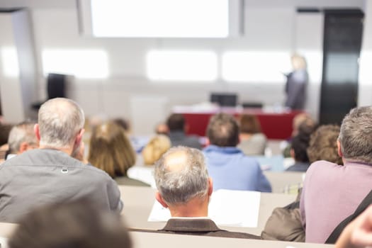 Speaker giving a talk in conference hall at business event. Audience at the conference hall. Business and Entrepreneurship concept. Focus on unrecognizable people in audience.