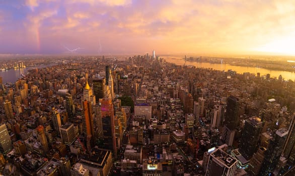 New York City skyline with Manhattan skyscrapers at dramatic vibrant after the storm sunset, USA. Rainbow and lightnings can be seen in background over Brooklyn bridge.
