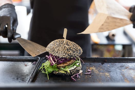 Chef making healthy vegetarian salmon burgers outdoor on open kitchen, odprta kuhna, international food festival event. Street food ready to be served on a food stall.
