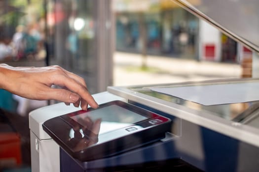 Woman's hand working on the copier's touchscreen on a street copy center