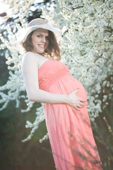 Beautiful pregnant woman relaxing outside in the Orchard