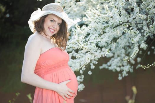 Young beautiful pregnant woman, blooming garden