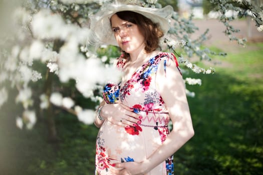 Beautiful pregnant woman relaxing outside in the Orchard