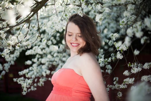 Young beautiful pregnant woman, blooming garden